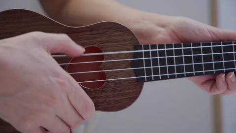 Sweet Note of Joy: Finger Plucks String on Ukulele with Heart Soundhole. 库存影片 320928526