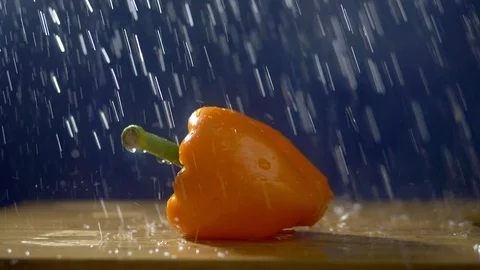 Sweet orange pepper on a dark background in the studio under jets of rain. Stock Footage 113282720
