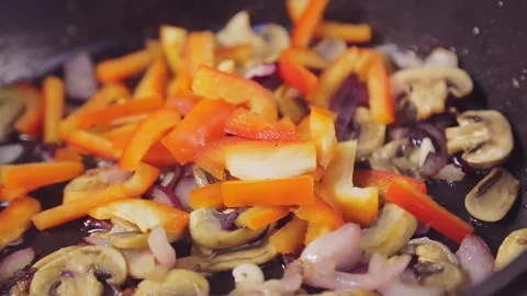 Sweet pepper falls on the vegetables fried in a pan and the spatula mixes Stock Footage 148771758