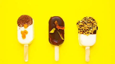 Sweet popsicles on yellow background. Mini dessert close up. Stock Photos
