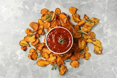 Sweet potato chips and bowl of sauce on grey background, top view Stock Photos