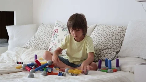 Sweet preschool child boy playing with toys indoor, sitting in bed Stock Footage