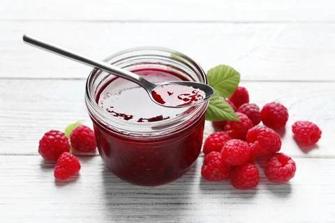 Sweet raspberry jam and fresh berries on white wooden table Stock Photos