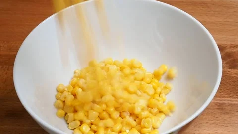 Sweet, raw canned corn is poured into a ceramic bowl for making a salad. 動画素材 346801039