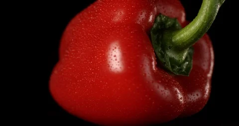 Sweet red bell pepper rotating on a black background with water drops. Shot on Stock Footage 106480986