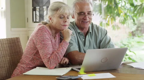 Sweet Senior couple using laptop computer to pay bills Stockbeeldmateriaal 47691092