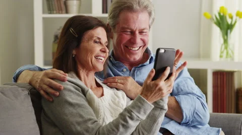 Sweet senior couple using smartphone on couch Stock Footage