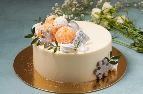 Sweet white chocolate cake decorated with tangerines on a blue background. ho Stock Photos