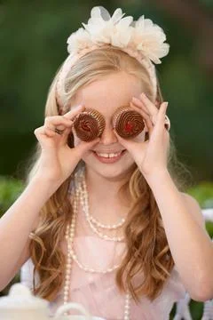 Sweetness personified. A young girl playfully holding cupcakes n front of her Stock Photos