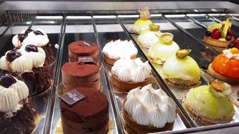 Sweets and small cakes with cream and chocolate or fruit on display behind the Stock Footage 256232608