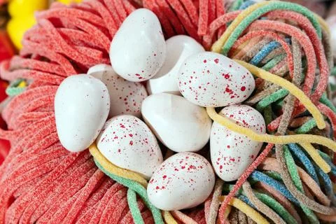 Sweets in the form of white quail Easter eggs lying in a nest of marmalade Stock Photos
