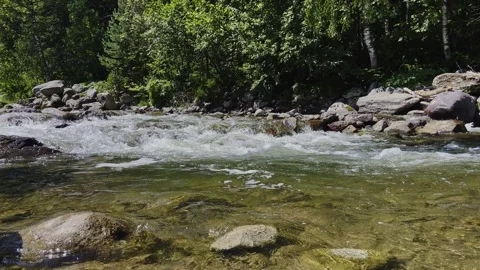 A swift stream of clean clear water flowing through stone boulders. Stock-Footage 247843072