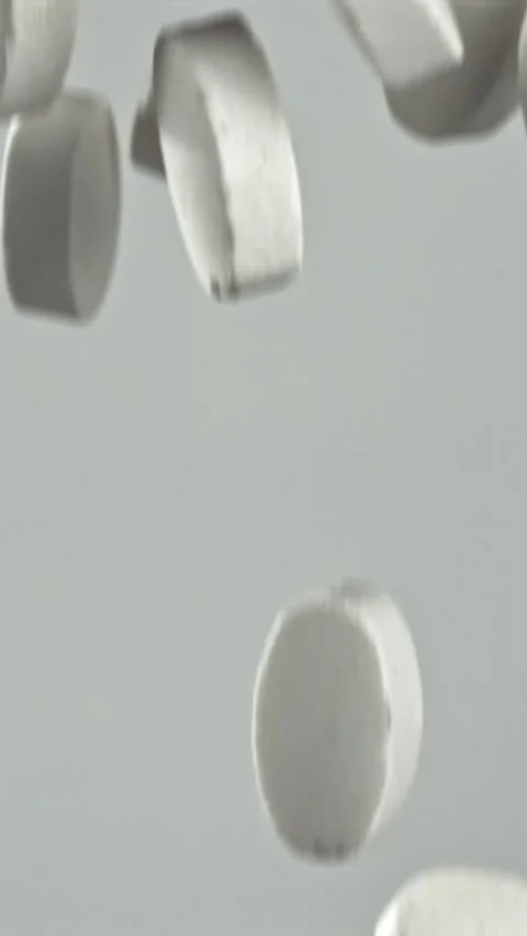 Swiftly falling tablets collide and disperse on soft gray backdrop Filmed on a Video stock 335396460