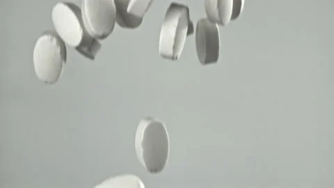 Swiftly falling tablets collide and disperse on soft gray backdrop Filmed on a Video stock 335424530