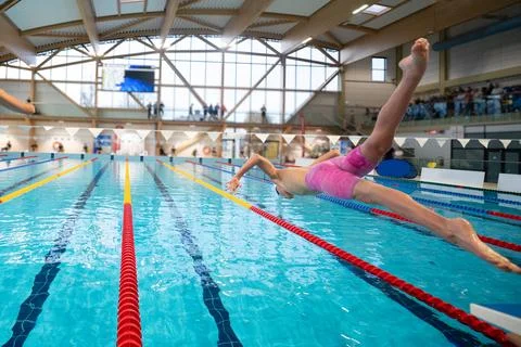Swimmer boy start from the starting table in the swimming pool Stock Photos