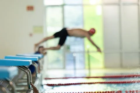 Swimmer diving into pool from starting block Stock Photos