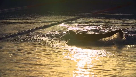 Swimmer does butterfly in open air pool at suneset. Vídeo Stock 71454650