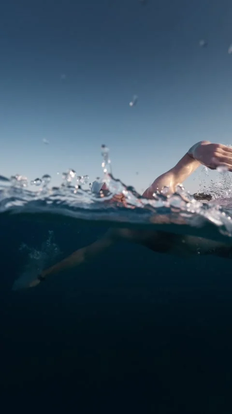 Swimmer gliding underwater with a distant beach on the horizon 스톡 동영상 344470170