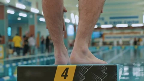 A swimmer jumps into the pool. A close-up slow-motion shot of the legs of a Stock Footage 255679990
