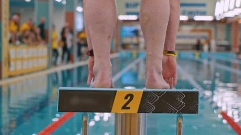 A swimmer jumps into the pool. Slow motion close-up shot of a swimmer's legs as Stock Footage 255680032