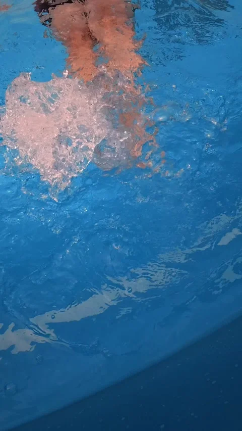 Swimmer kicking underwater in pool creating bubbles and ripples Stock Footage 342159174