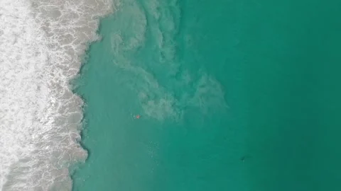 Swimmer in ocean waves, aerial view of turquoise water and sandy shore Stock Footage 336927065