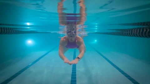 Swimmer performing breaststroke with split waterline view in indoor pool Video stock 328308369