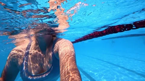 Swimmer performing underwater stroke beside lane rope in outdoor pool Stock Footage 342157013