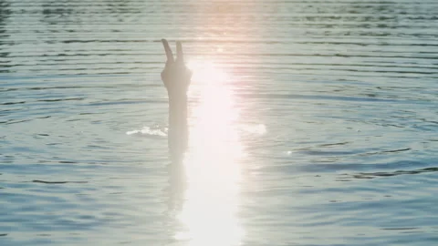 Swimmer Raising Hands and Making Peace Gesture at Sunset Stock Footage 344689096