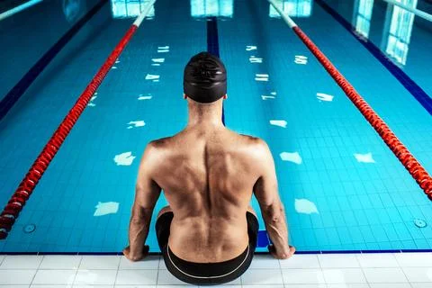 Swimmer sitting at the poolside, back view. Professional swimmer near the swi Foto stock