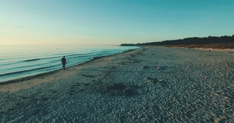Swimmer walking at the beach sunset alone lonely aerial drone coastline ocean Stock-Footage 153500708