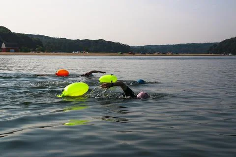 Swimmers Practice in Open Water With Bright Flotation Devices on a Sunny Day Stock Photos