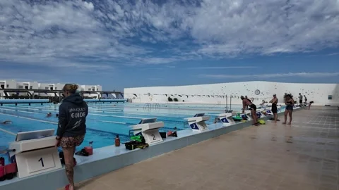Swimmers Prepare at Starting Blocks Beside Outdoor Lap Pool Stock Footage 345454915