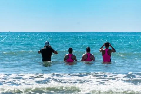 Swimmers wearing wetsuits preparing for open water race in summer Stock Photos