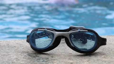 Swimming Goggles kept on the Edge of a Blue Swimming Pool Stock Footage 238847398