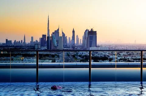 Swimming in infinity pool overlooking Dubai skyline at sunset Stock Photos
