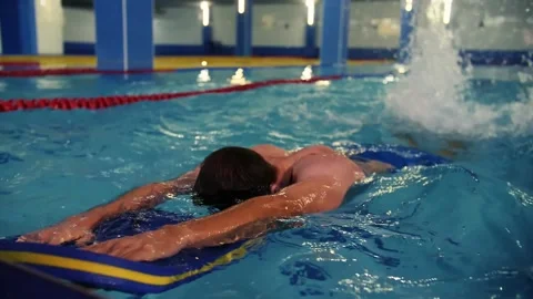 Swimming instructor teaches a young guy how to swim in the pool.Swimming in an Stock Footage 208633102