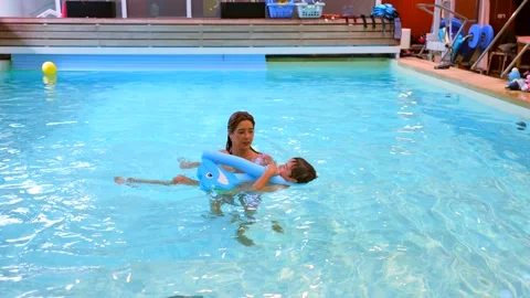 Swimming instructor teaching child using floatation device Stock Footage 313300825