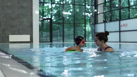 Swimming lesson class water instructor coach teaching little child kid to swim Stock Footage 157820588