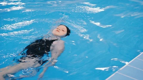 Swimming lessons for children in the pool - beautiful fair-skinned girl swims in Stock Footage 98288244