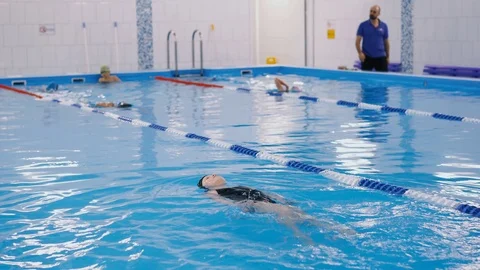Swimming lessons for children in the pool - beautiful fair-skinned girl swims in Stock-Footage 100283573