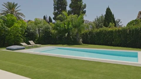 Swimming pool and empty sunbeds with trees and lawn. Stock Footage 161140480