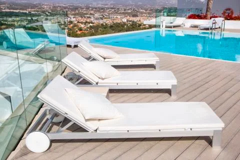 Swimming pool area with  white sun beds at the modern resort. Stock Photos