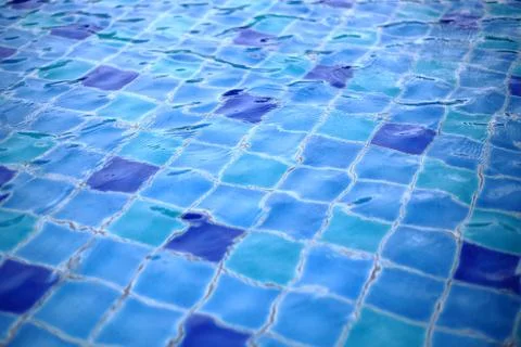 Swimming pool ceramic tiles covered in clear water. light blue tiles dotted w Stock Photos