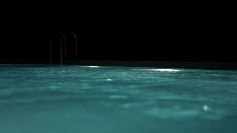Swimming pool with clear blue water and bright underwater lights at night. Stock Footage 340125190
