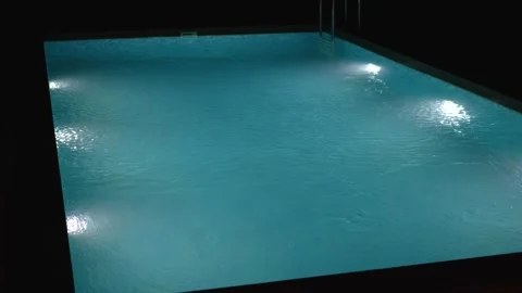 Swimming pool with clear blue water and bright underwater lights at night. Stock Footage 340125196