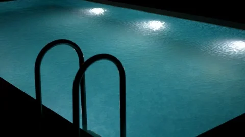 Swimming pool with clear blue water and bright underwater lights at night. Stock Footage 340125229