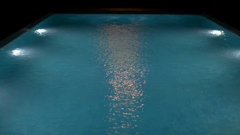 Swimming pool with clear blue water and bright underwater lights at night. Stock Footage 340125255
