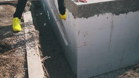 Swimming pool construction: a worker in bright shoes points at the aerated concr Stock Footage 312016128