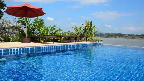 Swimming pool with daybed and red umbrella in Chiangrai ,Thailand Stock Footage 83791561